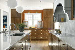Minneapolis kitchen with oak cabinetry, custom globe pendants, Cambria quartz countertops, and orange accents. 