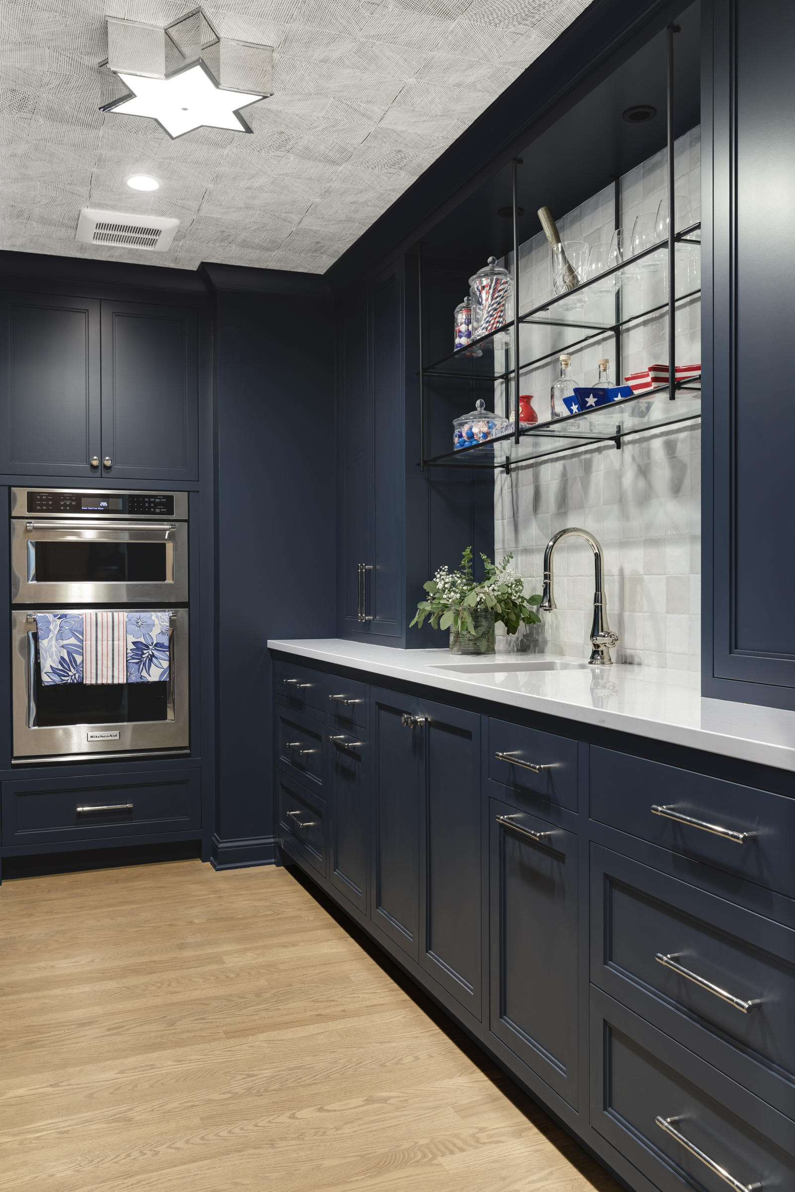 Butler's Pantry, dark blue cabinetry, hanging shelves, double ovens, sink, white cabinetry
