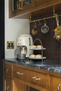 Butler's pantry with wood cabinetry, copper backsplash, mug hanging rack, coffee maker